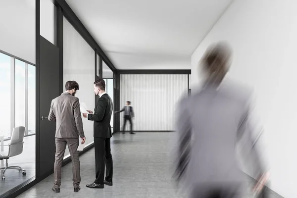 Люди ходят по офисному коридору с белыми и стеклянными стенами — стоковое фото
