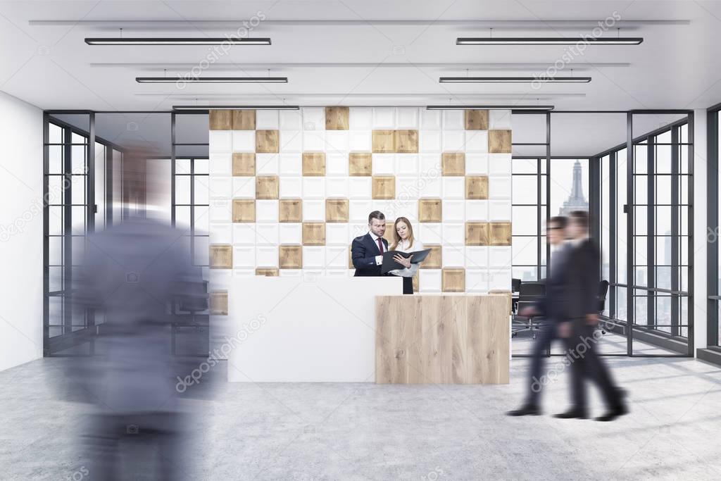 People in the office lobby with tiled white and wooden wall