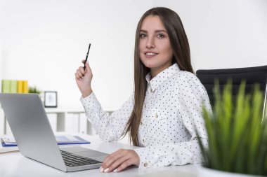 Puantiyeli gömlek gülümseyen ve bir kalem tutan güzel kız