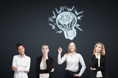 Dört kadın siyah duvara yakın beyin fırtınası. Ampul