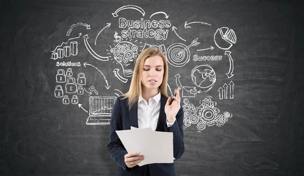 Gelukkige vrouw in de buurt van een schets van de strategie op een schoolbord — Stockfoto