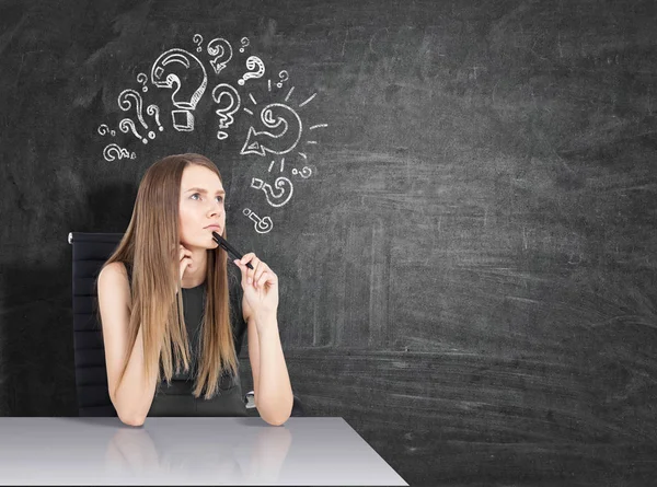 Chica en la mesa y signos de interrogación — Foto de Stock