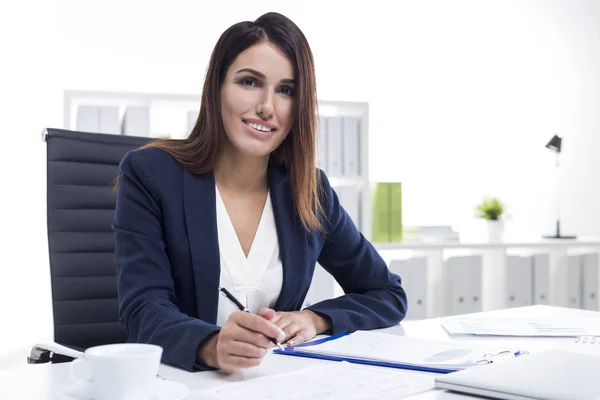 Smiling businesswoman reading and making notes — Stock Photo, Image