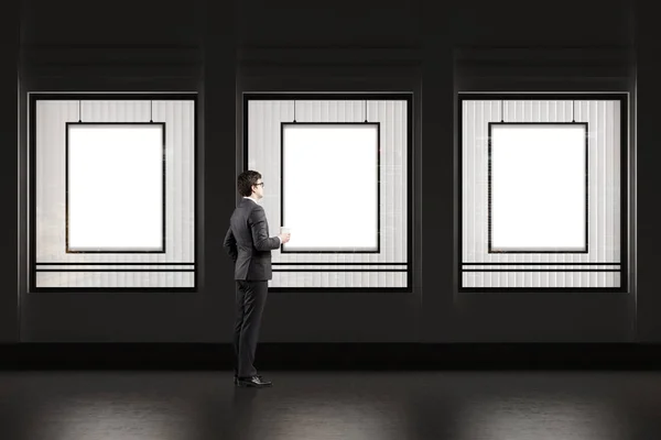 Man with coffee cup standing near a shop window with three frame — Stock Photo, Image