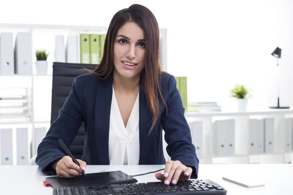 Mujer que trabaja con una tableta de lápiz en su oficina blanca — Foto de Stock