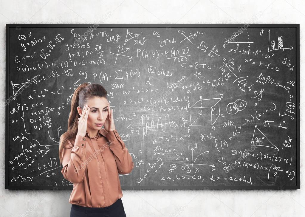 Stressed woman and formulas on blackboard