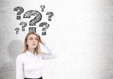 Sarışın kadın ve soru işaretleri beton duvar