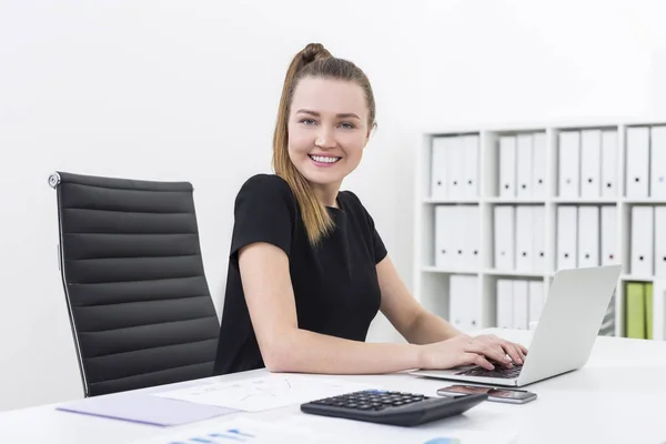 Side view of an office clerk typing and smiling — Stock Photo, Image