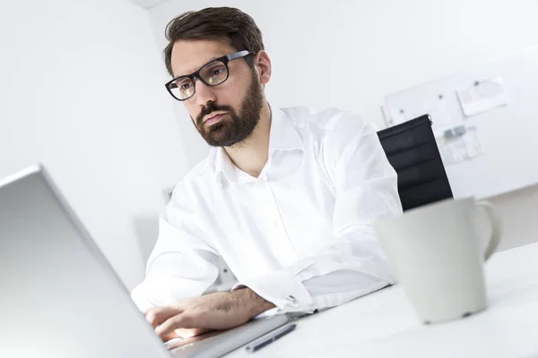 Giovane direttore barbuto digitando al computer portatile — Foto Stock