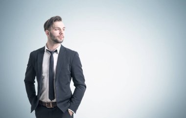 Kendine güvenen genç işadamı gri duvarının yakınında