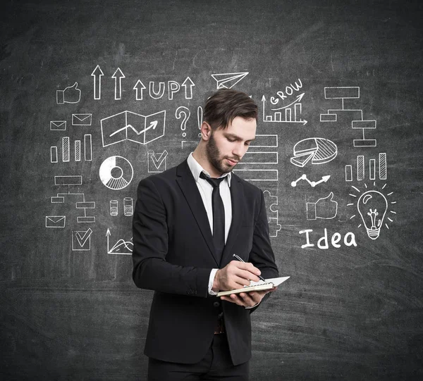 Hombre con cuaderno y boceto del plan de negocios — Foto de Stock