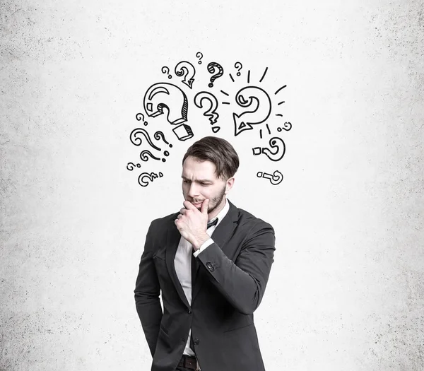 Pensive man near question marks — Stock Photo, Image