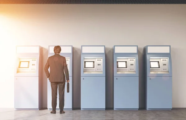 Rear view of a man near five ATM machines — Stock Photo, Image