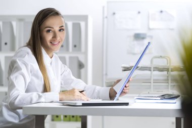 Elinde dosya olan beyaz bir bluz gülümseyen kadın