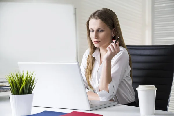 Porträt einer konzentrierten und schönen Geschäftsfrau, die eine weiße Bluse trägt und auf ihren Laptop-Bildschirm blickt. Attrappe. — Stockfoto