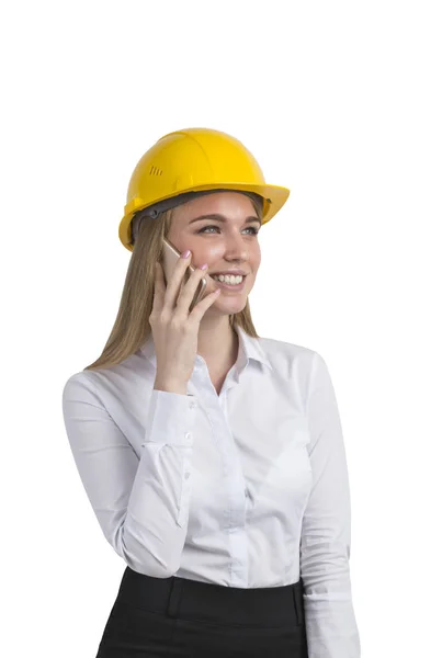Na białym tle portret businesswoman sobie żółty kask i biała bluzka i mówienie w swoim smartfonie. — Zdjęcie stockowe