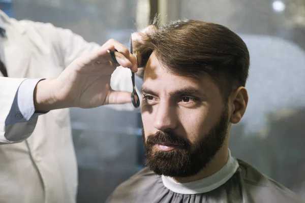 Vooraanzicht van een bebaarde zakenman met zijn haren knippen in een kapper. — Stockfoto