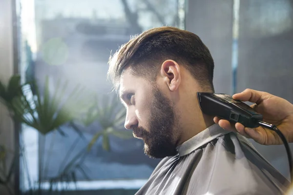 Close up of barbers hands trimming a serious businessmans hair. — Stock Photo, Image