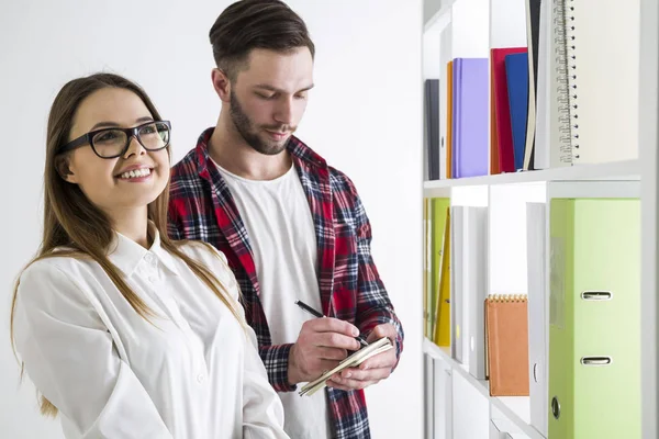 Vooraanzicht van een paar studenten in een bibliotheek. — Stockfoto