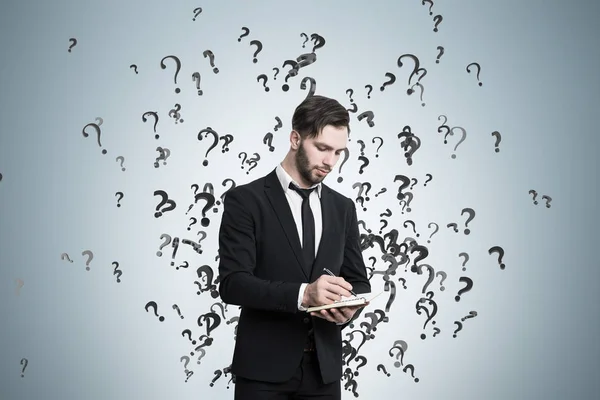 Writing man and question marks on gray wall — Stock Photo, Image