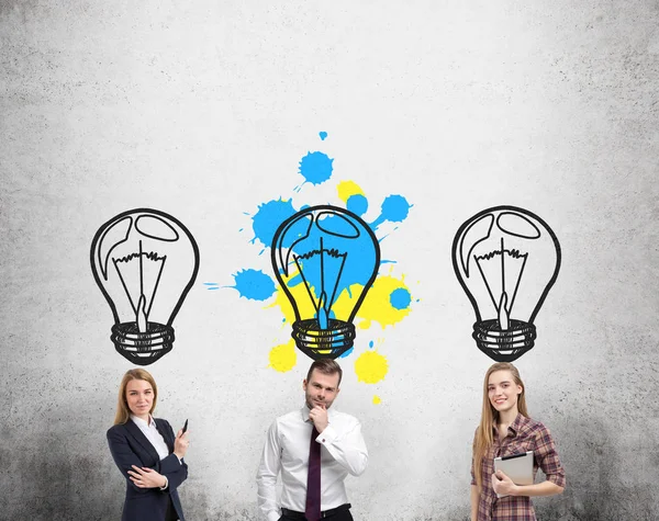 Two women and a man with a beard are standing near a concrete wall. — Stock Photo, Image