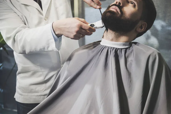 businessmans beard being trimmed.