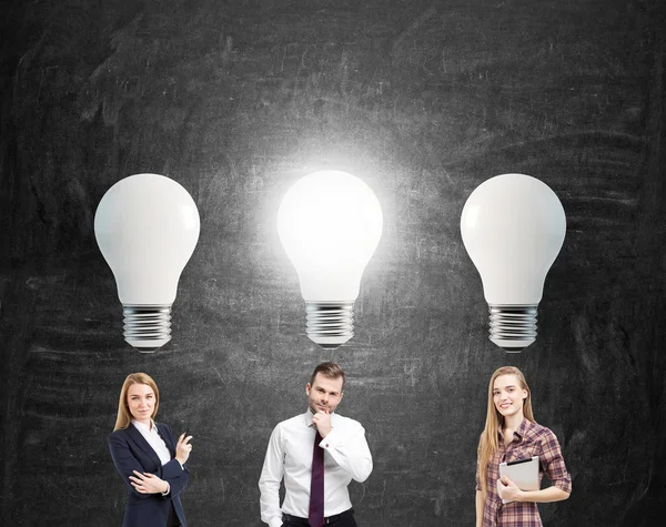 Two women and man and big light bulbs. — Stock Photo, Image