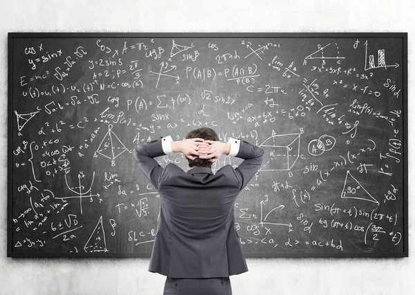 Zakenman kijken naar formules op blackboard — Stockfoto