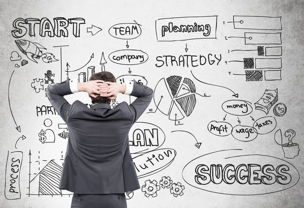 Businessman looking at start up sketch on concrete — Stock Photo, Image