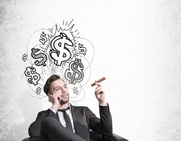 Finance concept. Attractive european businessman talking on phone while smoking cigar on concrete background with drawn dollars. — Stock Photo, Image