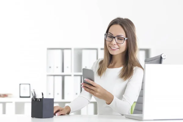 Mooie vrouw in glazen met telefoon in kantoor — Stockfoto