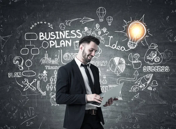 Uomo con laptop, business plan e lampadina — Foto Stock