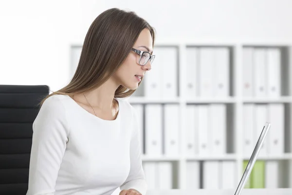 Tampilan samping gadis berbaju putih dekat laptop di kantor — Stok Foto