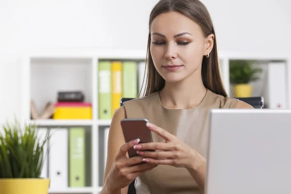 Vrouw in beige kijken telefoon scherm — Stockfoto