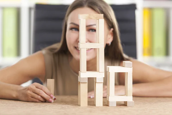 Menina alegre está brincando com tijolos de madeira — Fotografia de Stock