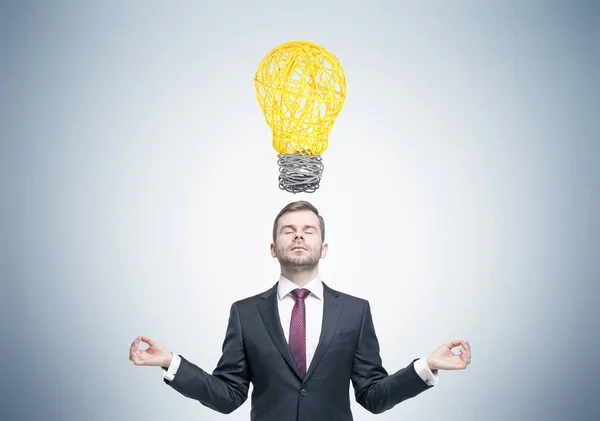 Empresário meditante e lâmpada — Fotografia de Stock