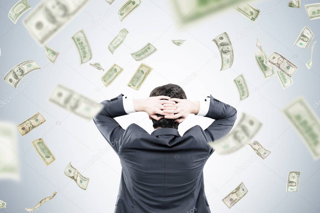 Man with hands behind head and dollars falling