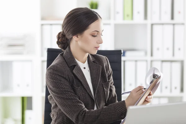 Side view of a woman in brown with a clipboard — Stock Photo, Image