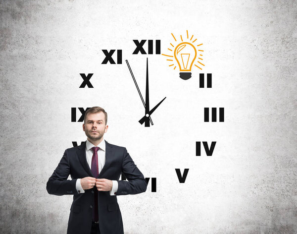 Человек и часы с лампочкой на бетоне
