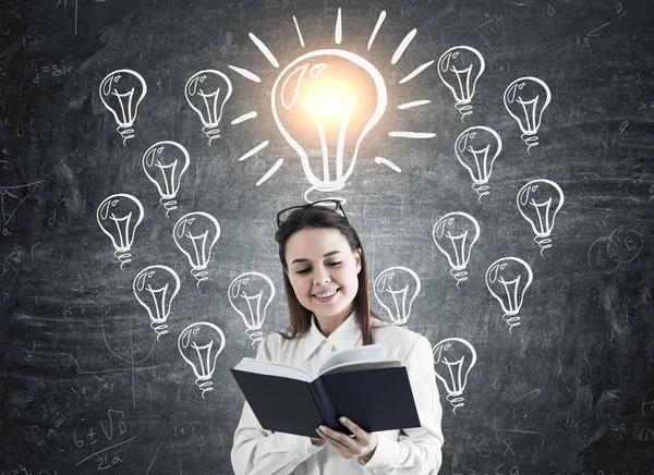 Chica con un libro y bombillas brillantes —  Fotos de Stock