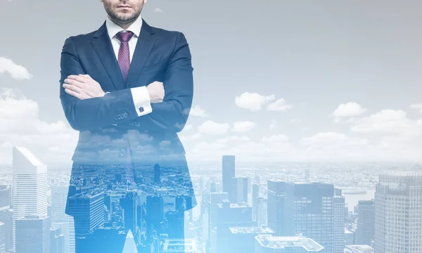 Doppelbelichtung eines bis zur Unkenntlichkeit verschränkten Geschäftsmannes, der vor einem Stadtpanorama steht. Attrappe — Stockbild Mann mit gekreuzten Armen und eine Stadt — Stockfoto