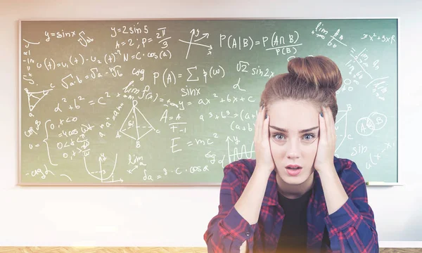 Stressed teen girl, formulas on blackboard, toned — Stock Photo, Image