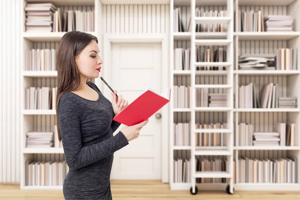 Sidovy av en kvinna med bok i vita bibliotek — Stockfoto