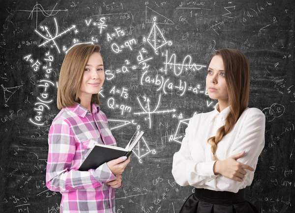 Två flickor och formler på blackboard — Stockfoto