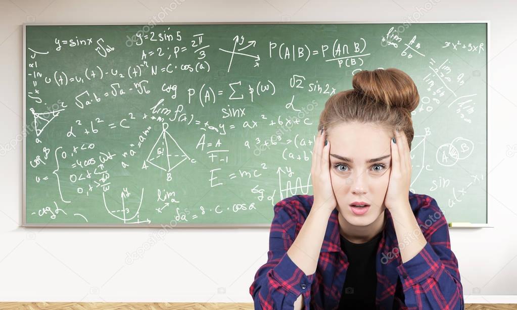 Stressed teen girl and formulas on blackboard