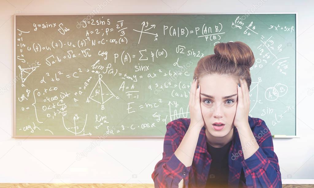 Stressed teen girl, formulas on blackboard, toned