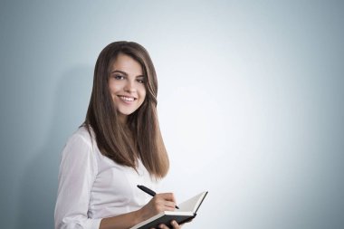 Kadın bir defter, gri duvar ile