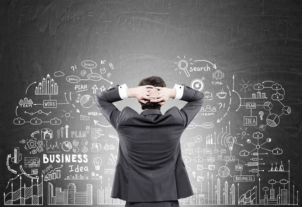 Man looking at business idea on blackboard — Stock Photo, Image