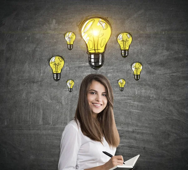 Girl with notebook and many light bulbs — Stock Photo, Image