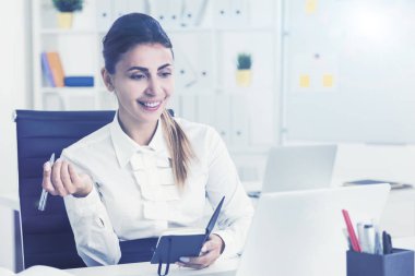 Not Defteri ile gülümseyen kahverengi saçlı kadın